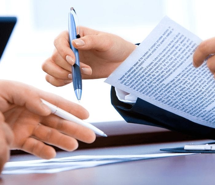 two peoples hands looking over a contract with pen