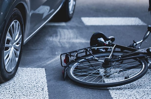 car next to a fallen bicycle in accident