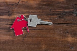 house keychain with single key on wood background