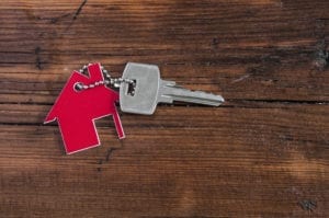 house keychain with single key on wood background