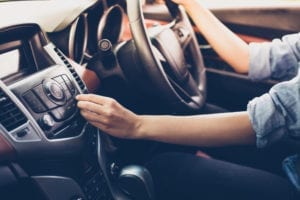 person adjusting radio while driving in a car
