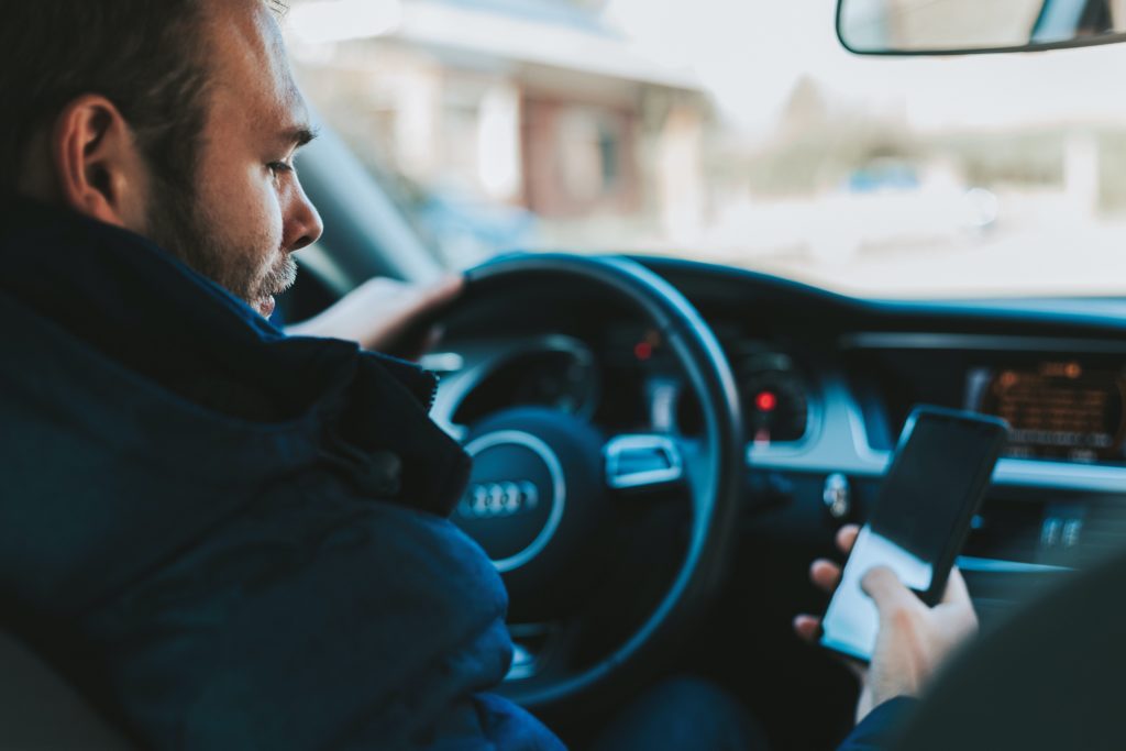 man looking at phone and not paying attention while driving