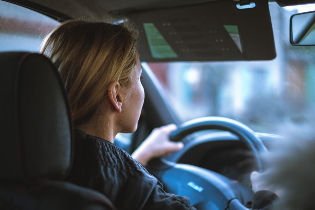 lady driving with visor down with two hands on steering wheel