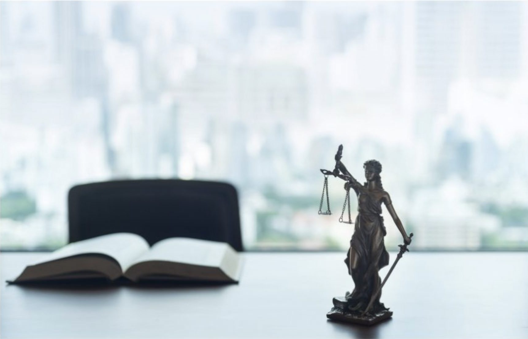 empty chair with book in front of it and scale of justice to the right of image