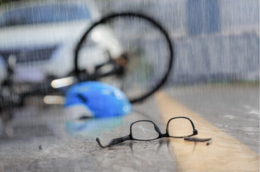 raining image of glasses with a bike accident in the background