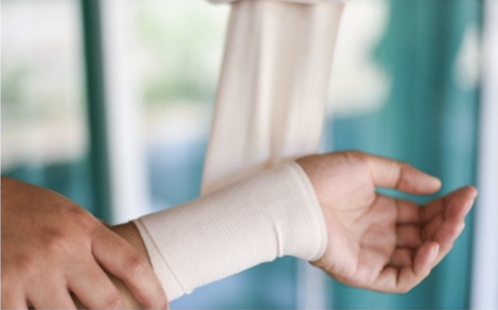 injured left wrist of individual being wrapped with an ace bandage.