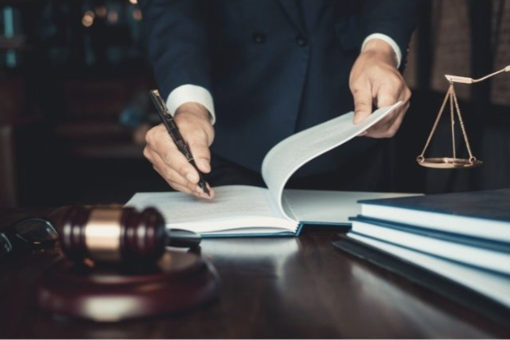 hand holding fountain pen writing in a book with gavel in foreground