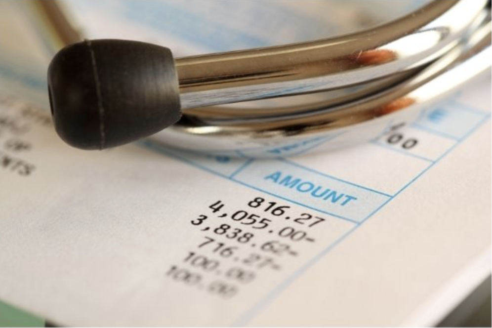 stethoscope on top of a piece of paper that looks to be a bill with amounts due