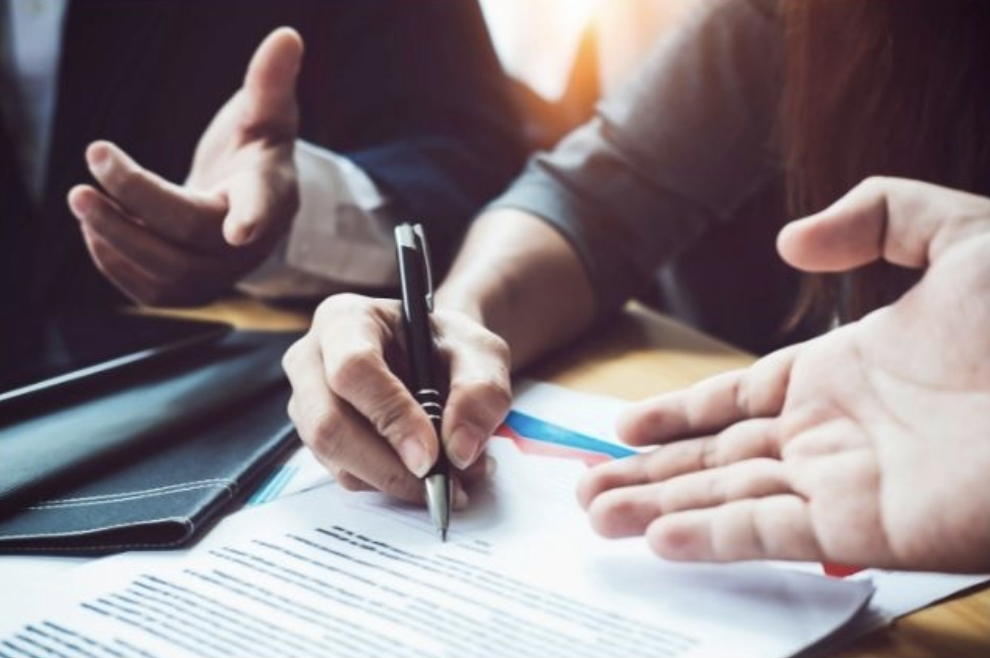 3 people discussing a contract together, closeup of their hands only, medical bills and suing the at fault driver of a car accident