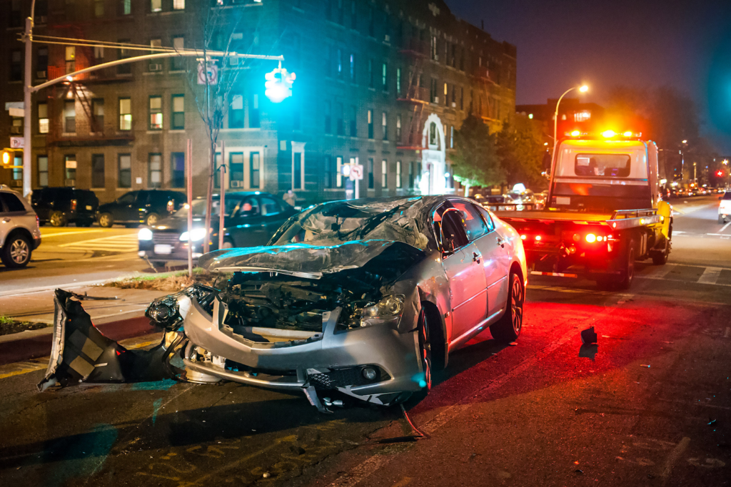 night time shot of a car in a severe drunk driving accident with towtruck picking it up