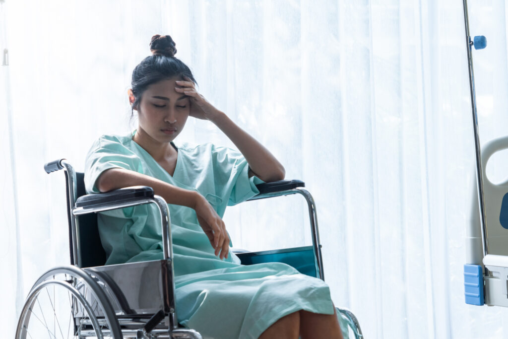 Serious patient sitting on wheelchair in hospital ward after a single vehicle car accident due to defect