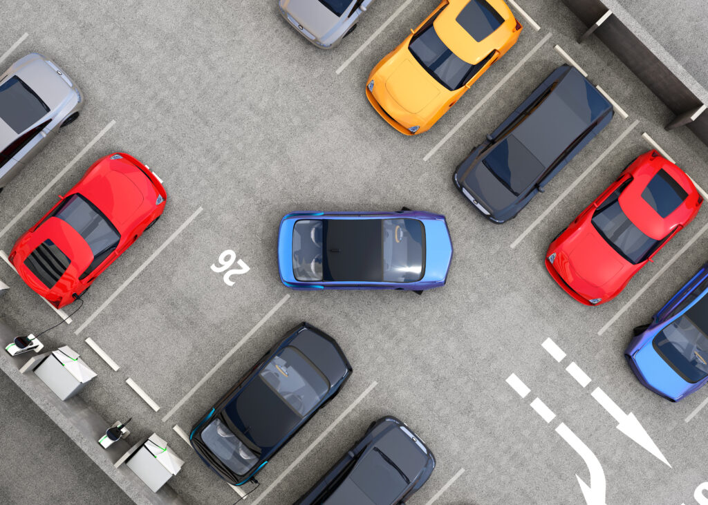Aerial view of parking lot and blue car backing out of a space self driving autonomous cars