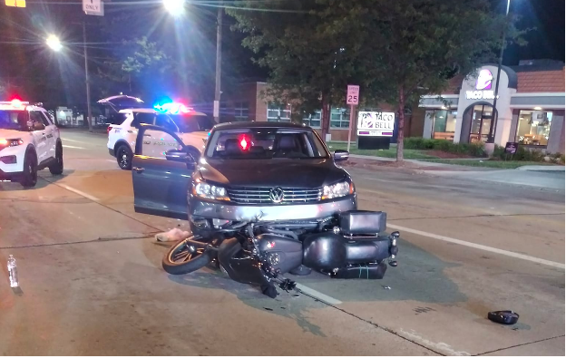 night time car accident with motorcycle in front of the car with police cars behind the accident