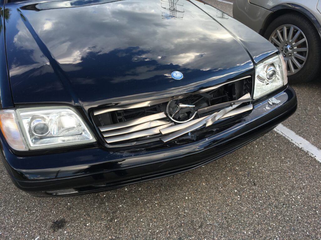 car accident in a parking lot, front end of black car damaged