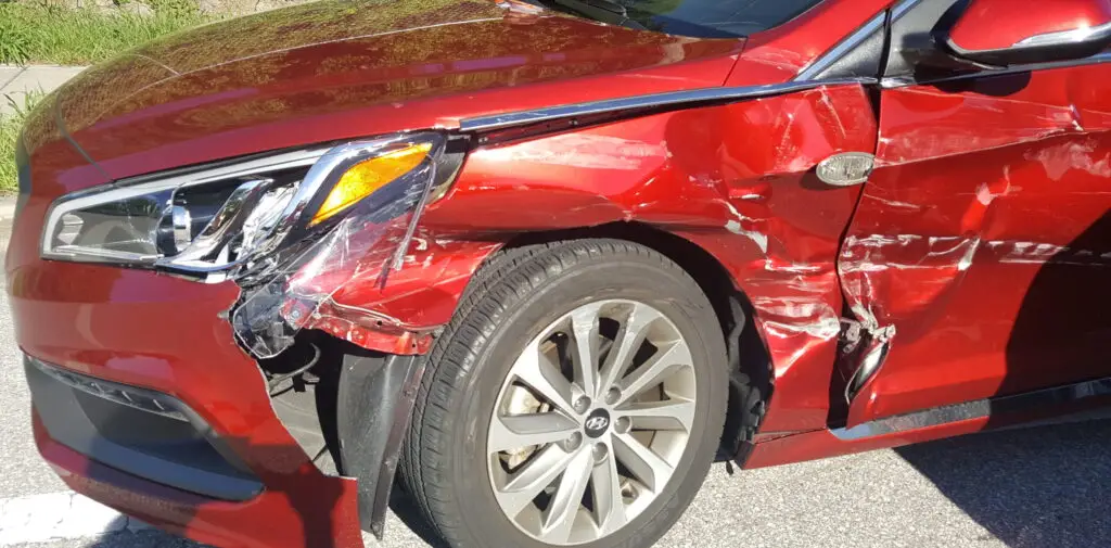red car with a dented and scratched drivers side