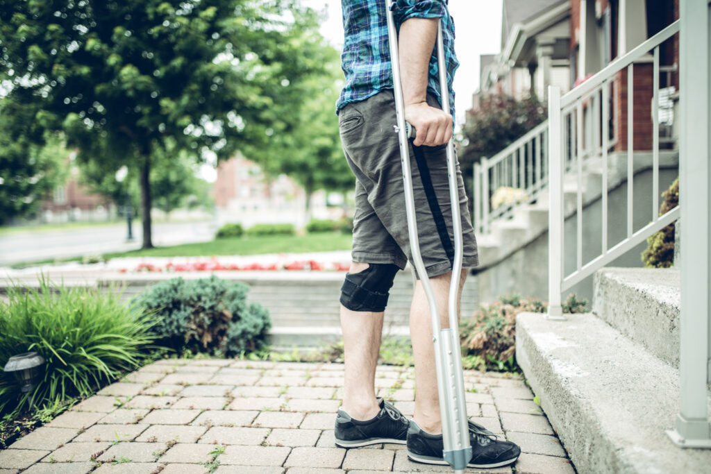 man using crutch after having knee sprain accident from a personal  injury accident, medical bills concept