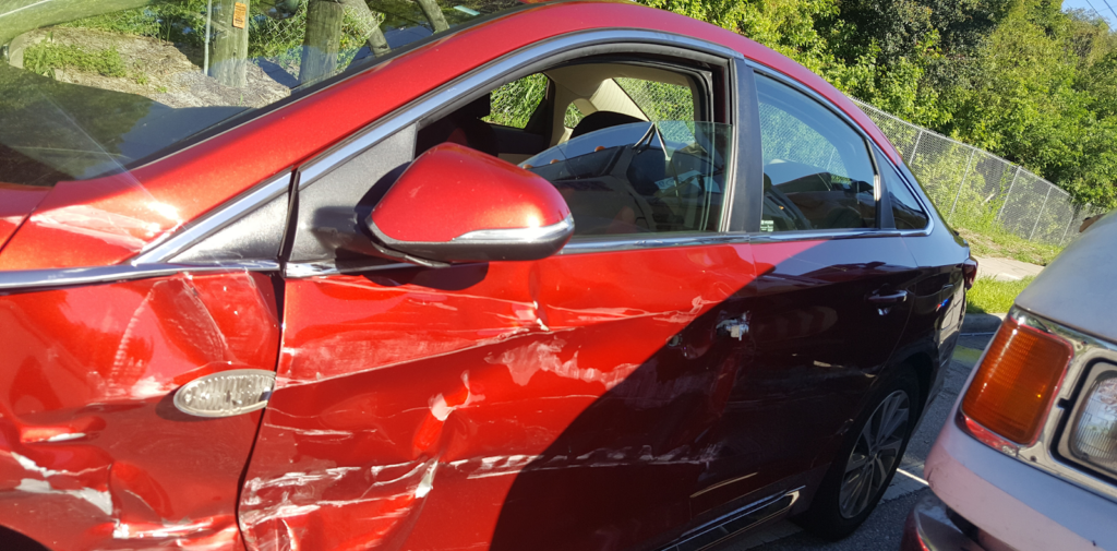 single car accident scene, red car is hit on the side due to swerving out of the way