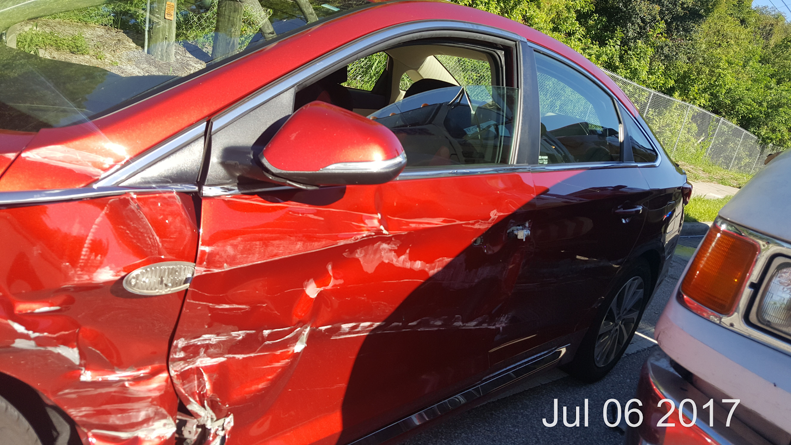 sideswipe accident in clearwater, red car with scratches and dents on the front drivers side