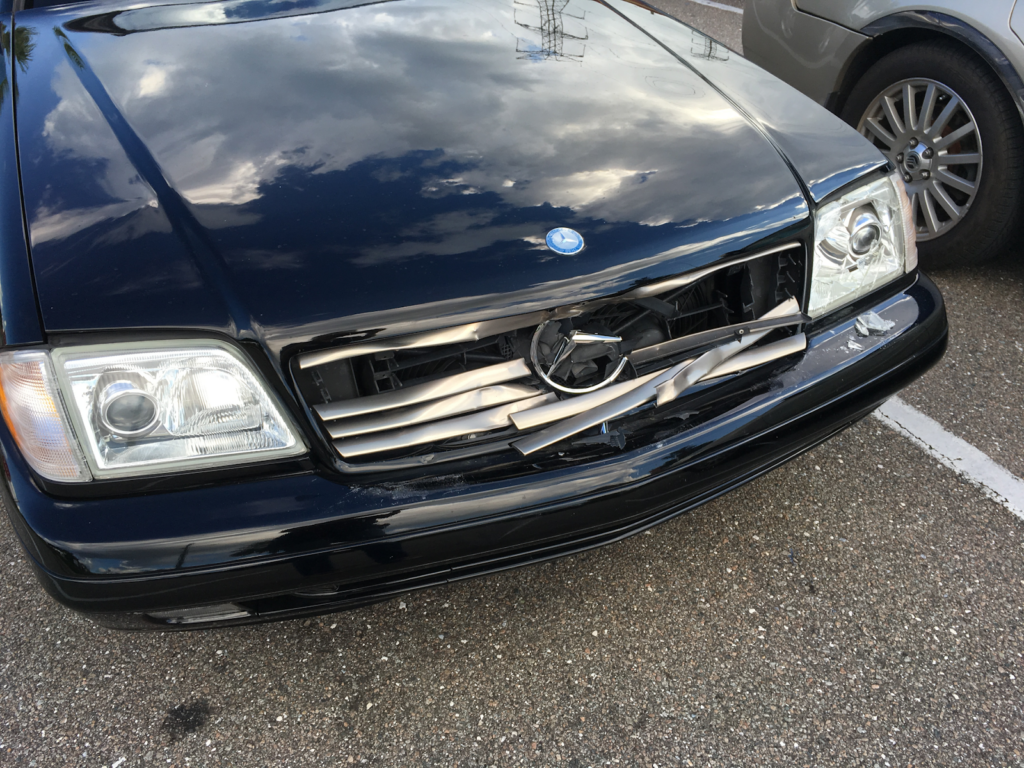 close up of a damaged hood and bumper of a mercedes in a car accident from a rear end accident in the fall around "fall behind" time change
