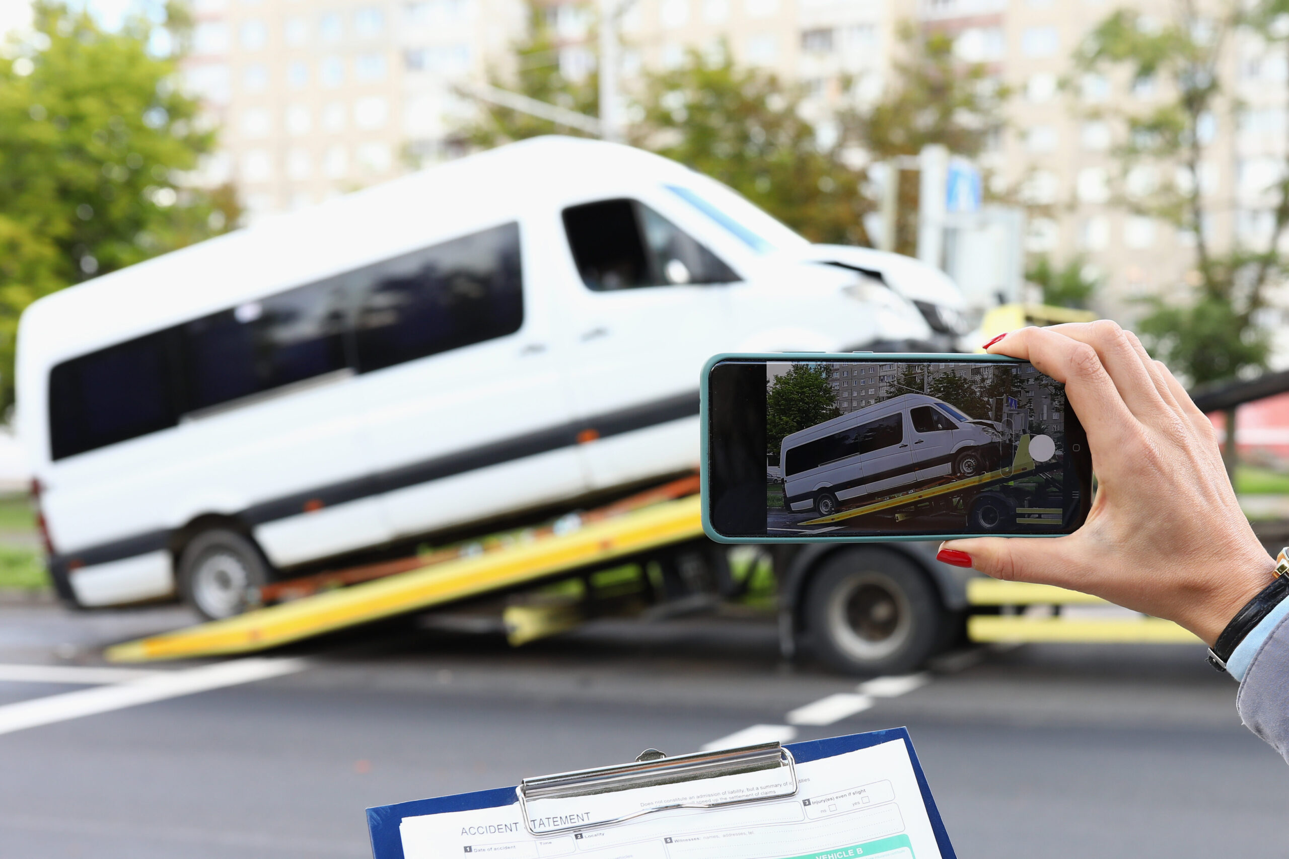Woman insurance agent takes a picture of broken minibus on smartphone.
