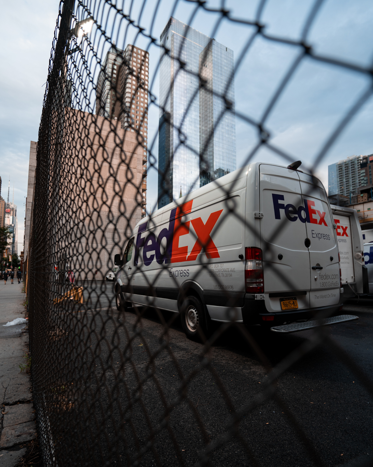point of view from behind a fence of a fedex truck driving onn the road