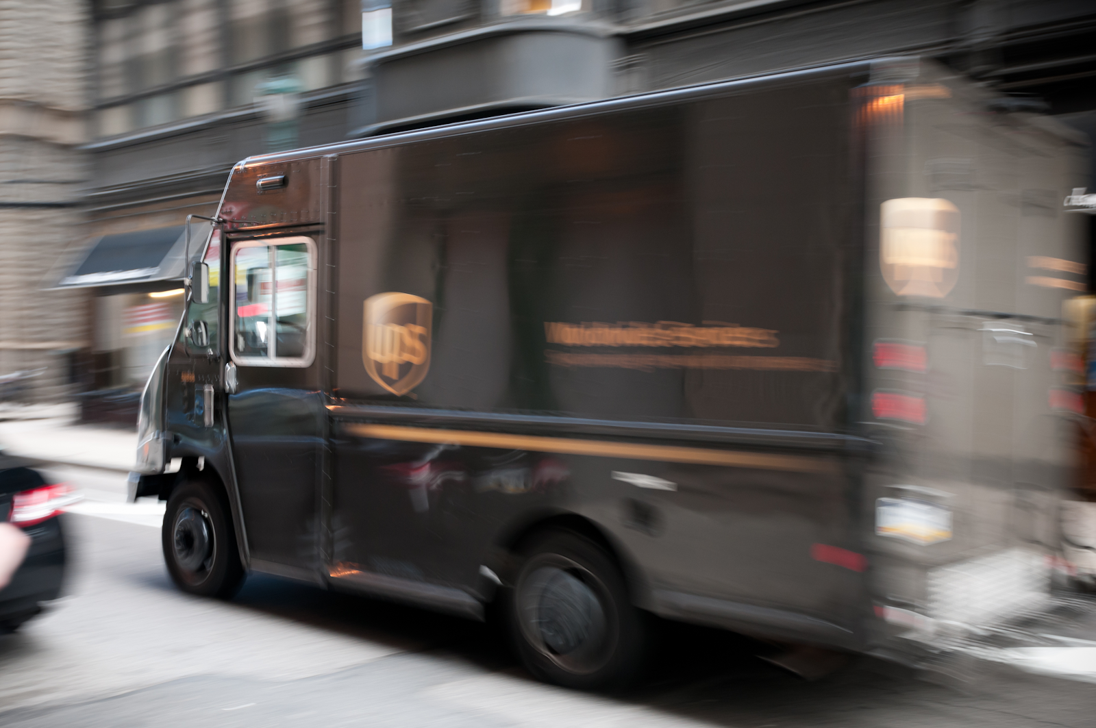 United parcel service UPS driver in a ups vehicle speeding down the road