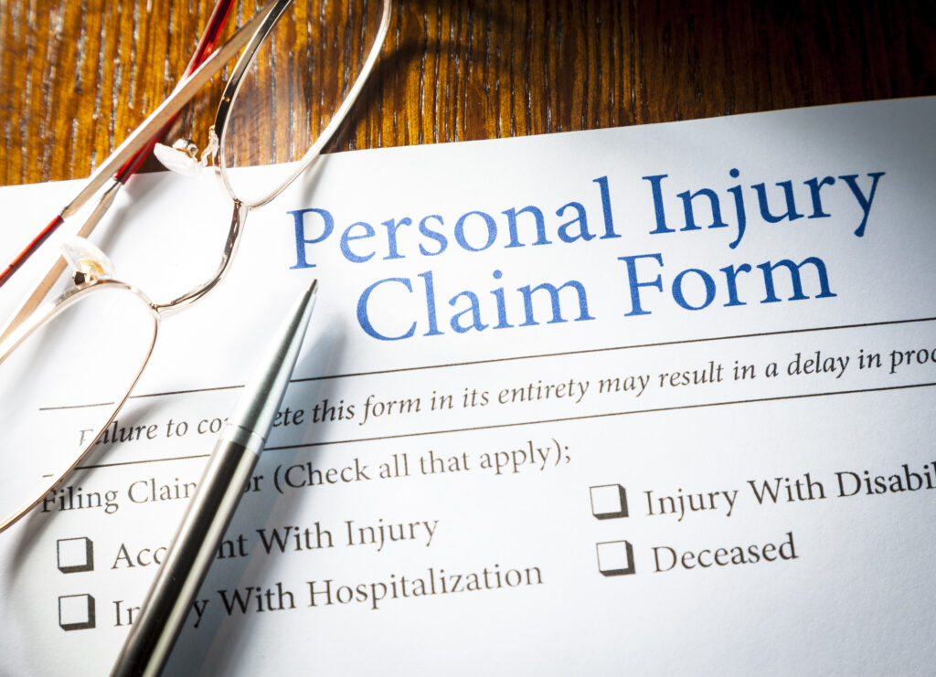 Personal Injury Claim form with pen and glasses on a table of a personal injury lawyer