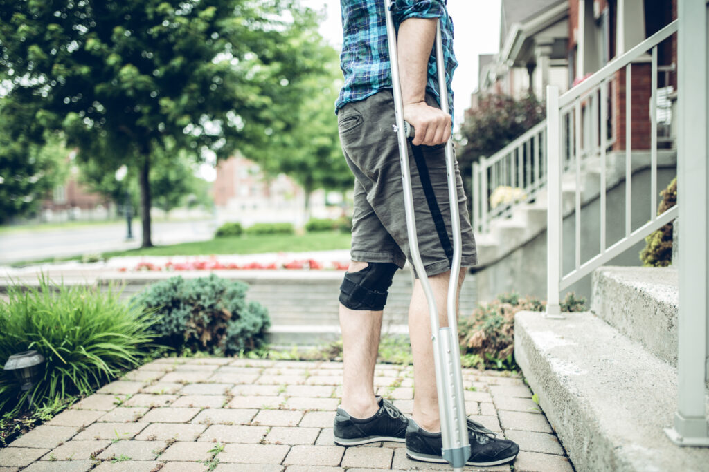 man using crutch after having knee sprain in a personal injury accident