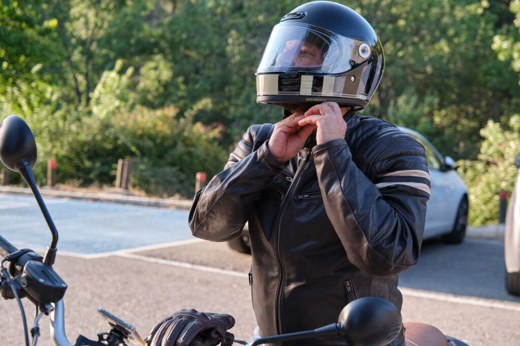 motorcyclist buckling a helmet for a ride in brooksville to avoid injuries in case of a car accident, motorcycle crashes theme