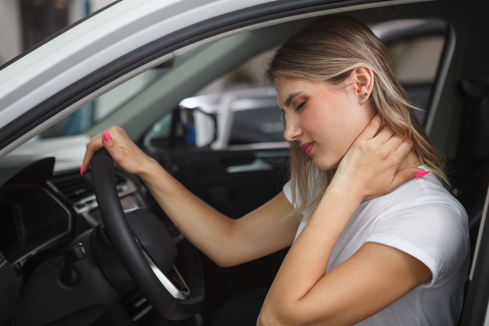 A woman grabs her neck and winces in pain after a car accident.