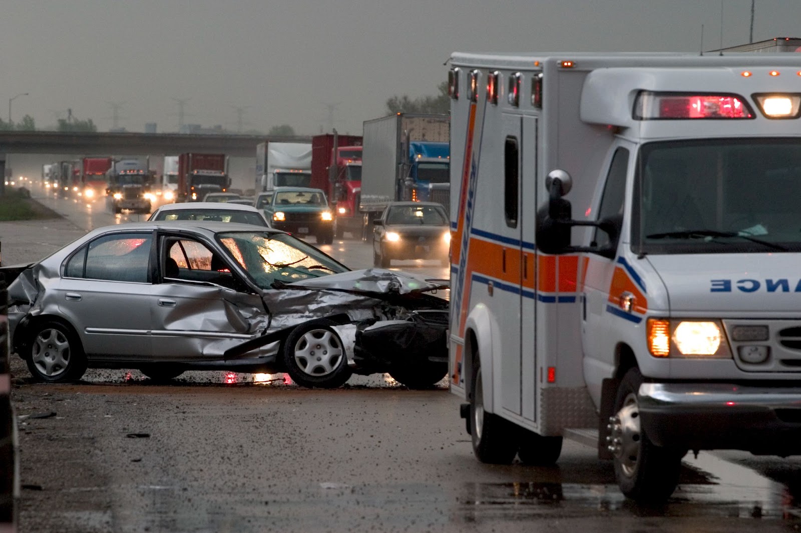 An Ambulance arrives at the scene of a car accident on a busy freeway.