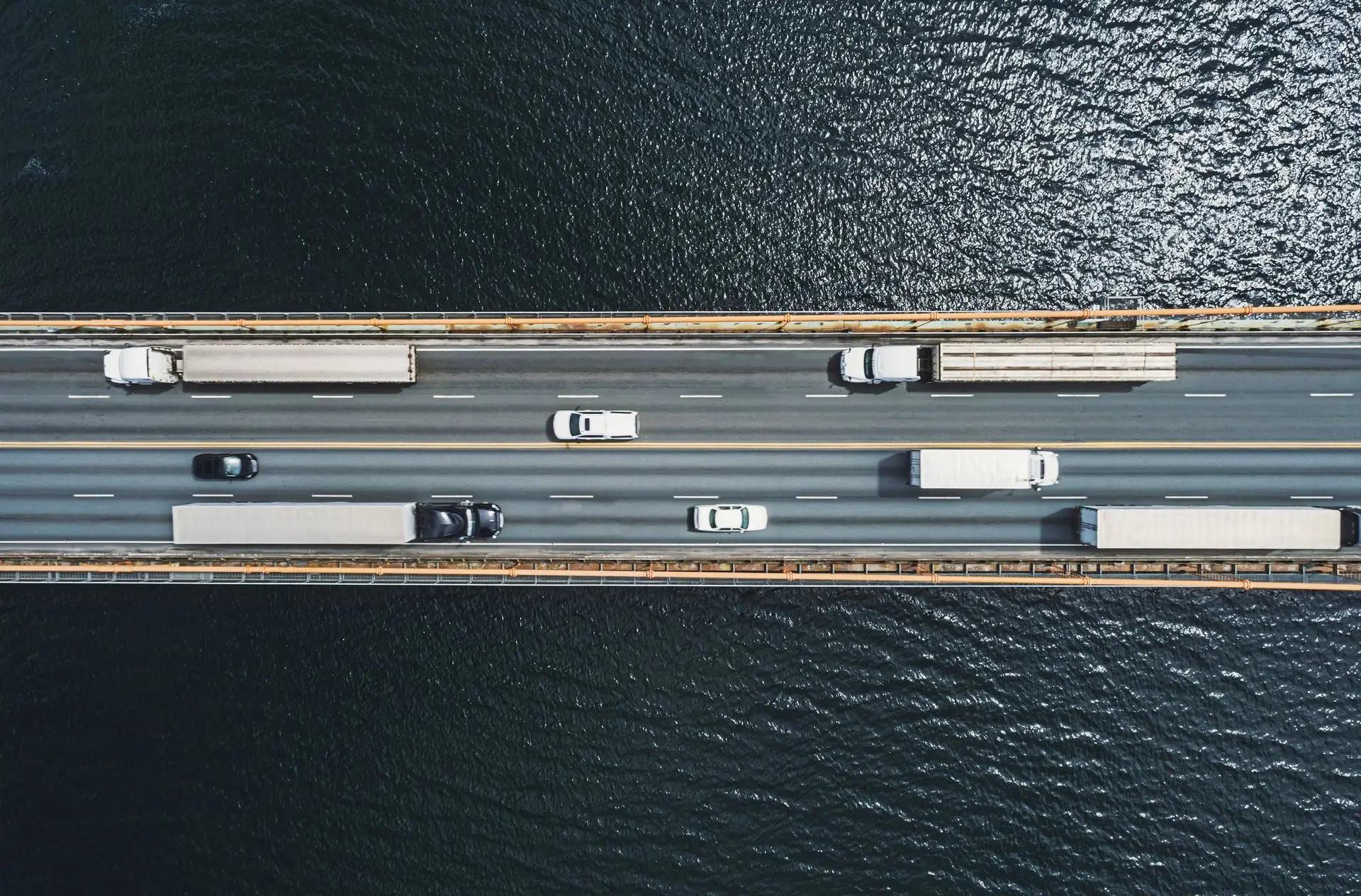 Semi-trucks and cars travel in both directions on a bridge in Florida