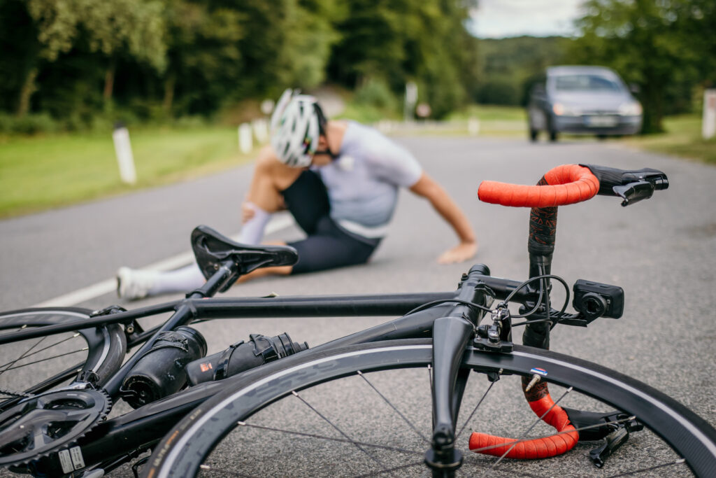 an injured rider holds their leg in pain after a bicycle accident with a motor vehicle.