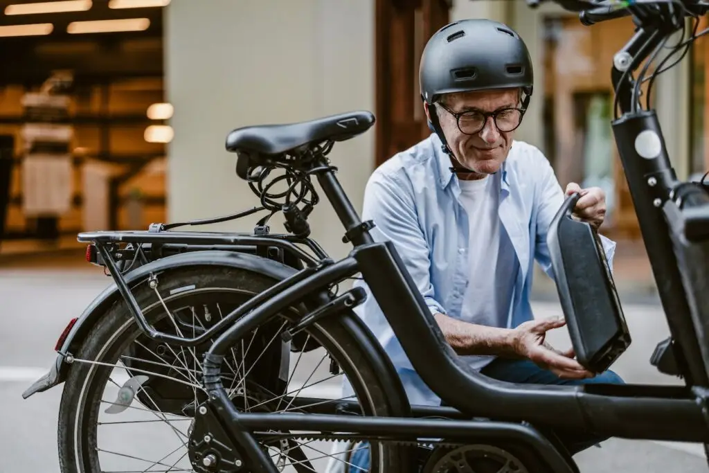A man is seen changing the battery on his electric bicycle. 