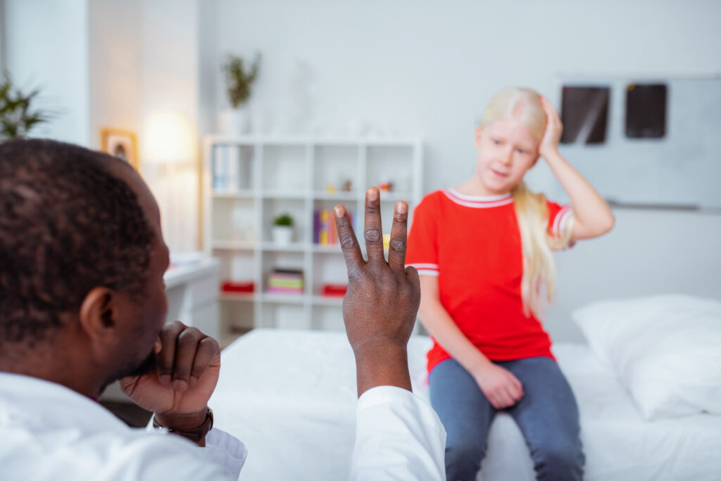 A doctor holds up three fingers to determine the severity of head injury his patient, a young girl, received while she was a passenger in a car accident.