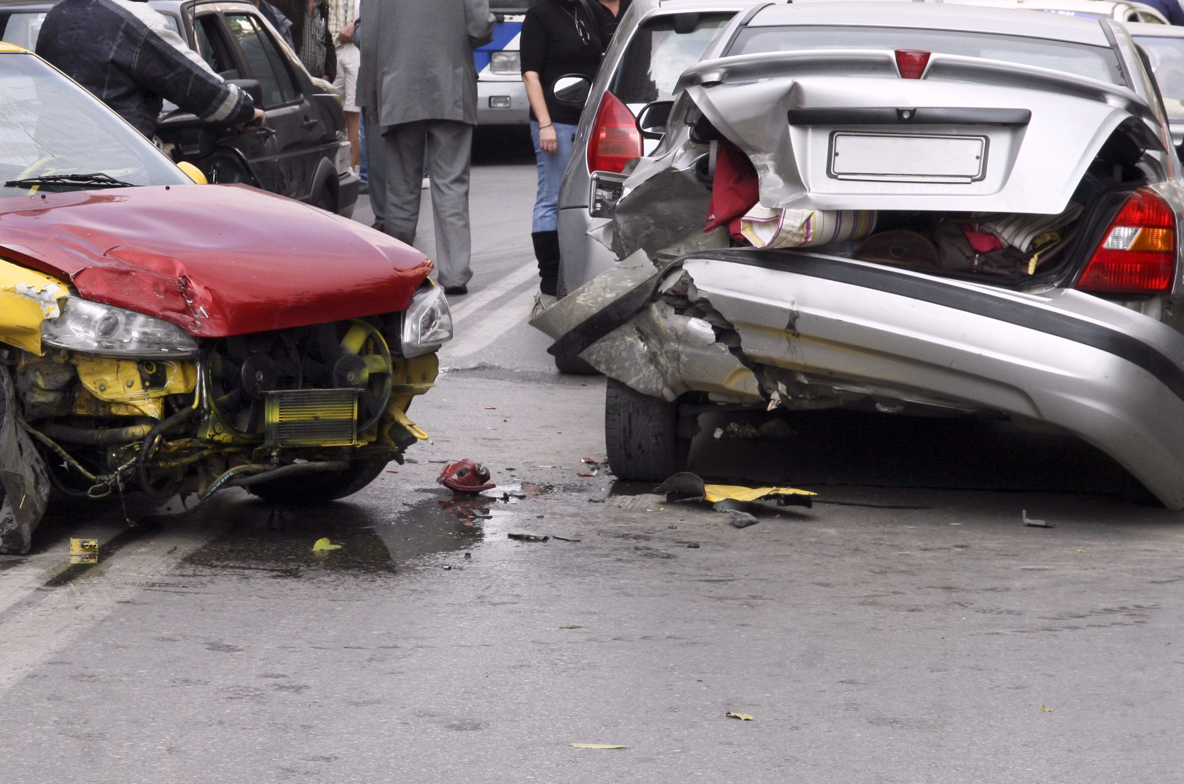 two damaged passenger vehicles after an accident on a busy street.