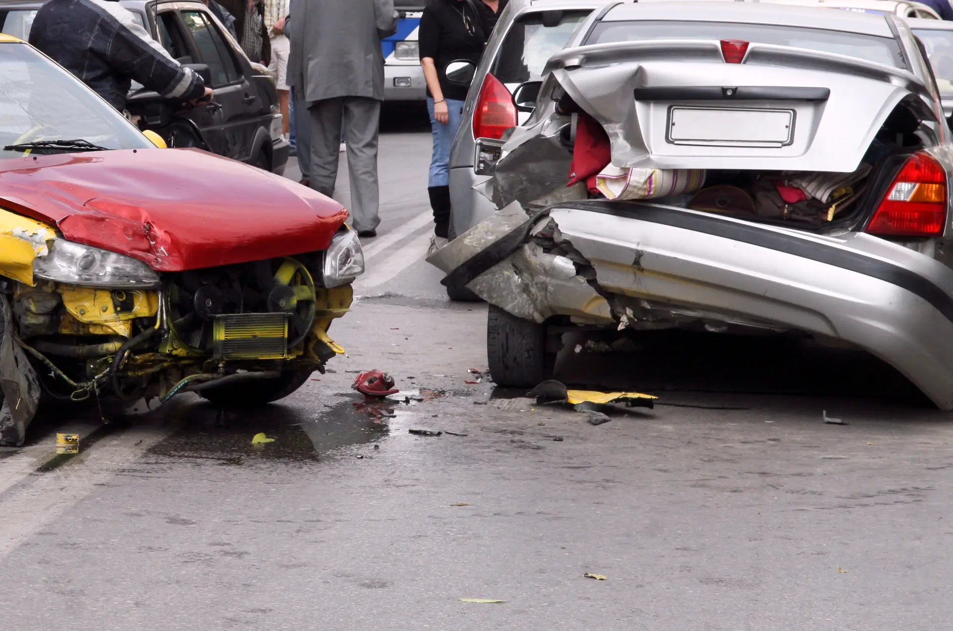 two damaged passenger vehicles after an accident on a busy street.
