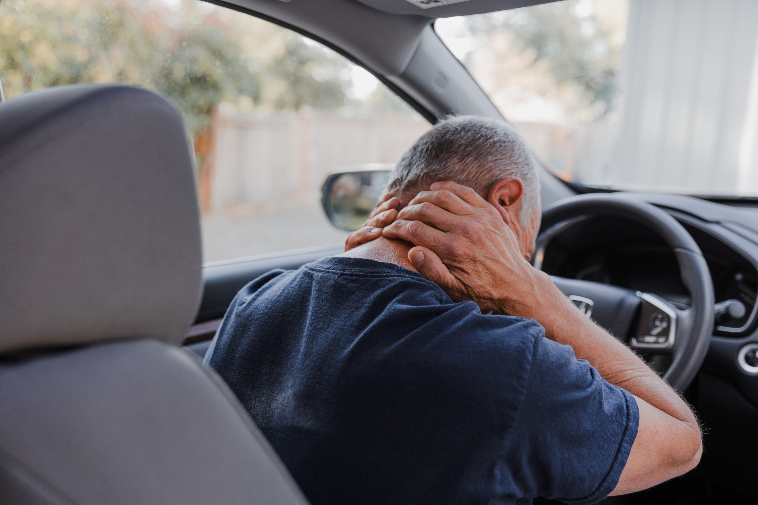 A man grabs his neck in pain after sustaining a whiplash injury in a car accident.