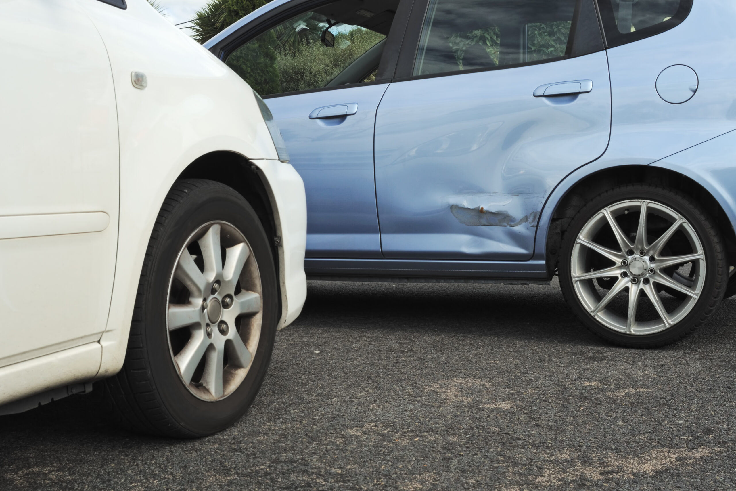 A close up view of a white car that has been in a t-bone accident with a blue car. 
