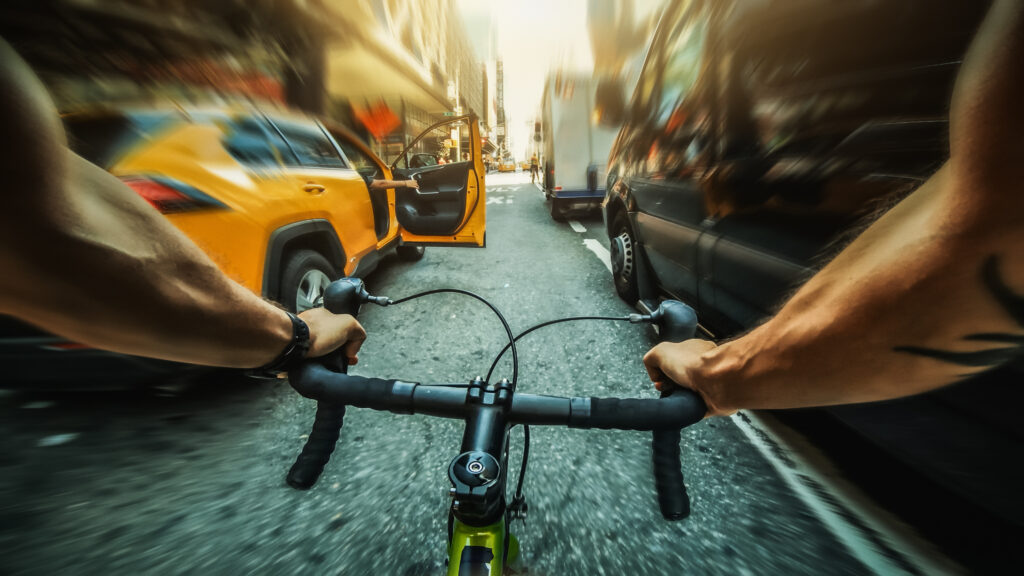 A first-person view of a cyclist traveling at a high speed when a passenger getting out of a taxi cab almost causes a dooring accident.