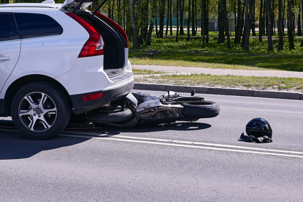 a white SUV on top of a motorcycle in the middle of the road after a fatal accident.