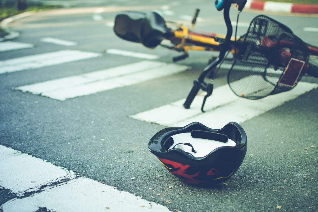A bicycle and a helmet laying on the ground in the middle of a crosswalk after an accident.
