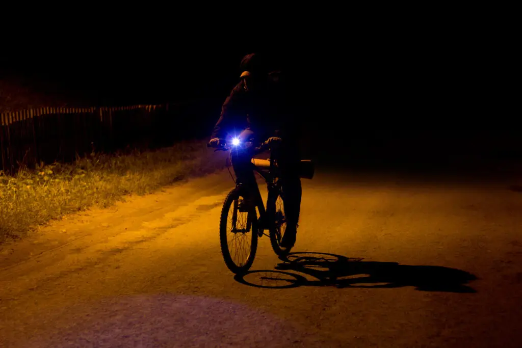 A cyclist peddles down the road at night.