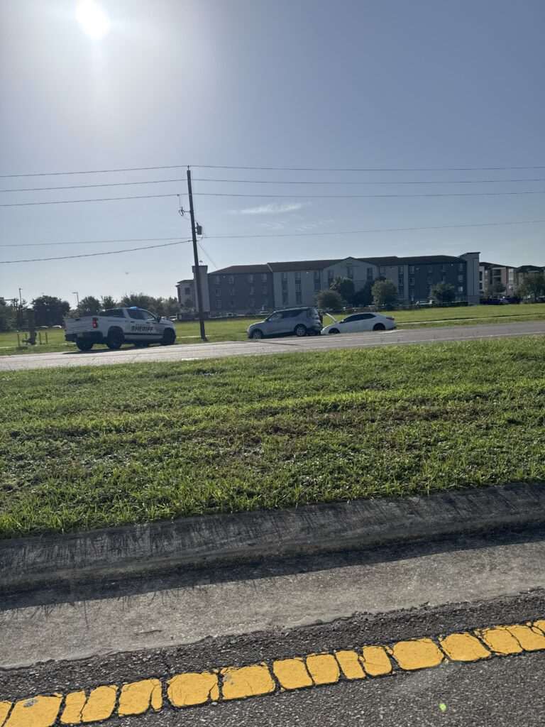 A car accident off of W Falkenburg Road in Tampa with two cars off the road in a ditch with a Sheriff vehicle on the scene. 